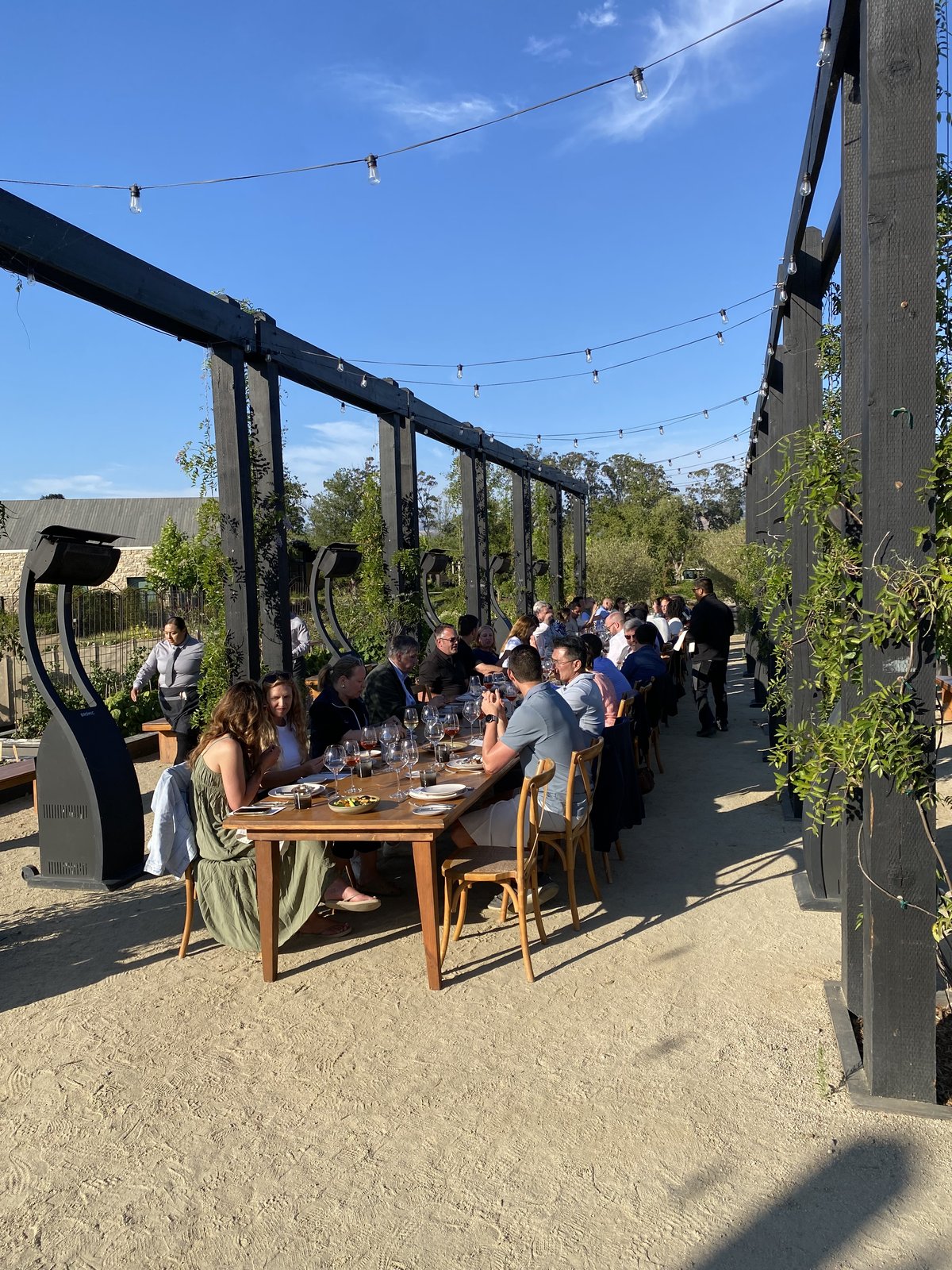 Founders dining along the pergola table at golden hour