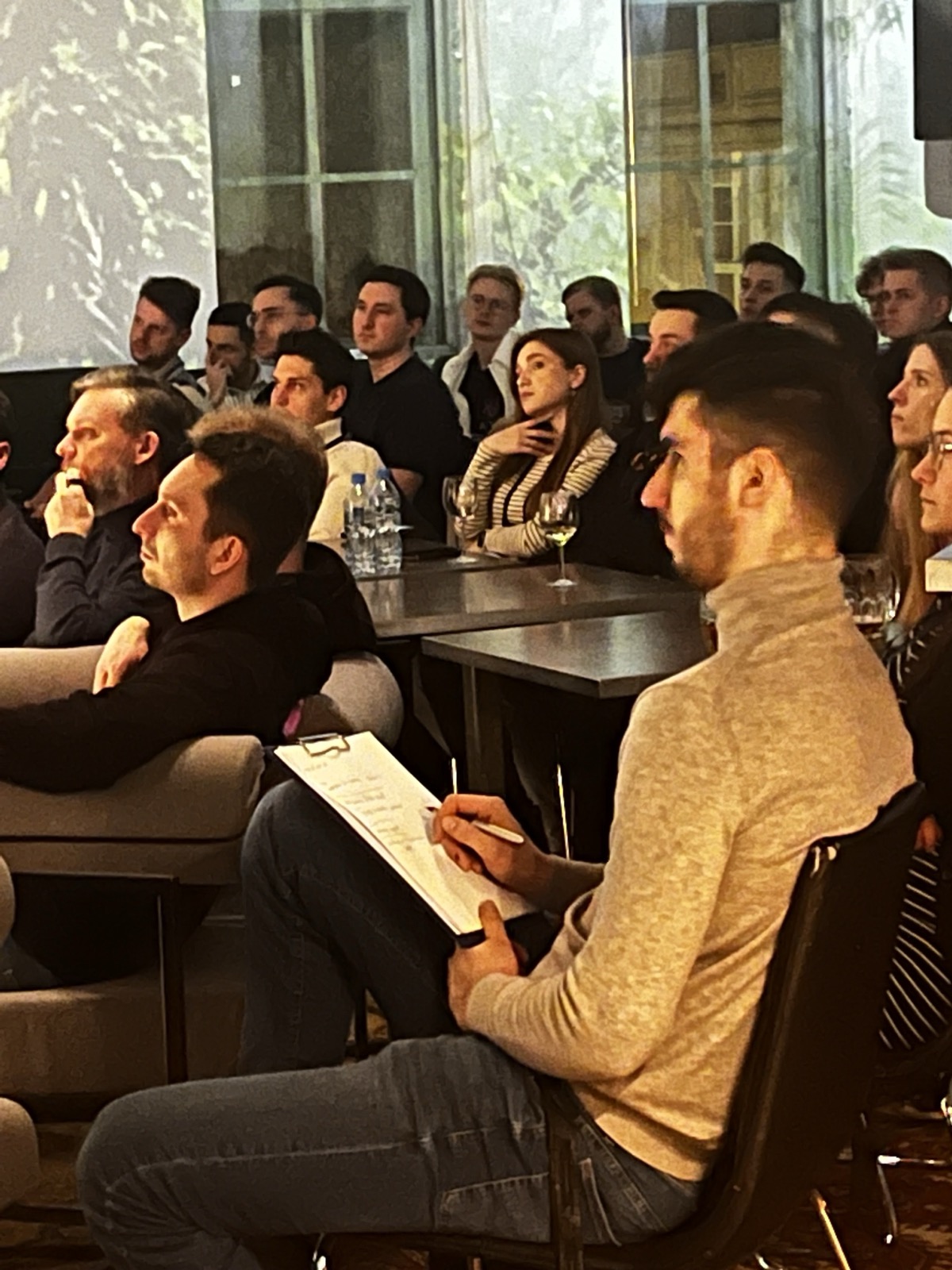 Founders listening intently, one taking notes, during a talk