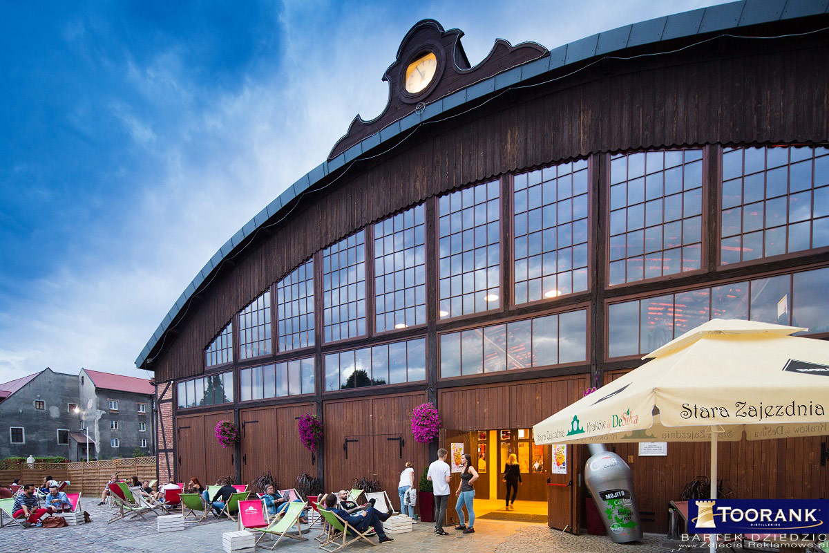 The restored 1913 tram-depot exterior of Stara Zajezdnia by DeSilva at dusk, with deckchairs on the courtyard