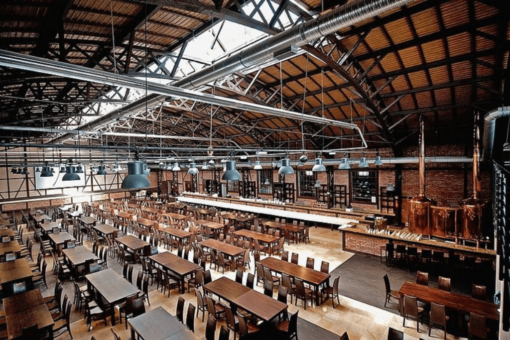 The industrial timber-and-brick main hall of Stara Zajezdnia, set with long tables under exposed steel trusses and hanging lamps